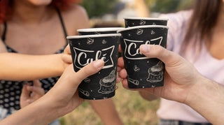 Custom branded black coffee cups grouped together in an outdoor lifestyle shot