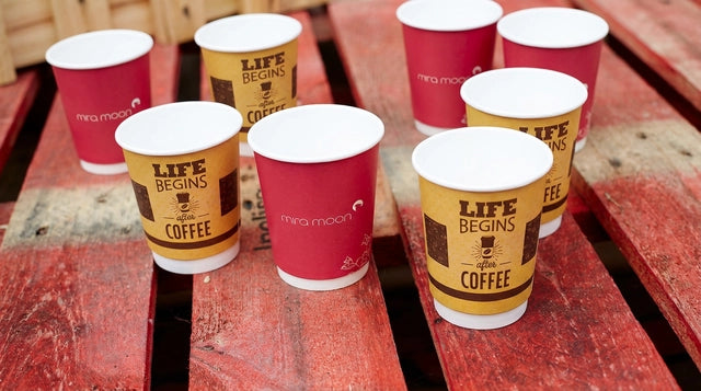 Custom branded paper cups arranged across red wooden pallets